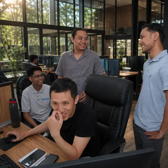 Doodex developers gathered around a monitor during a daily review