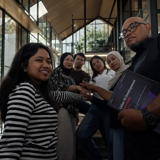 Doodex team on the studio stairs holding an Odoo development handbook